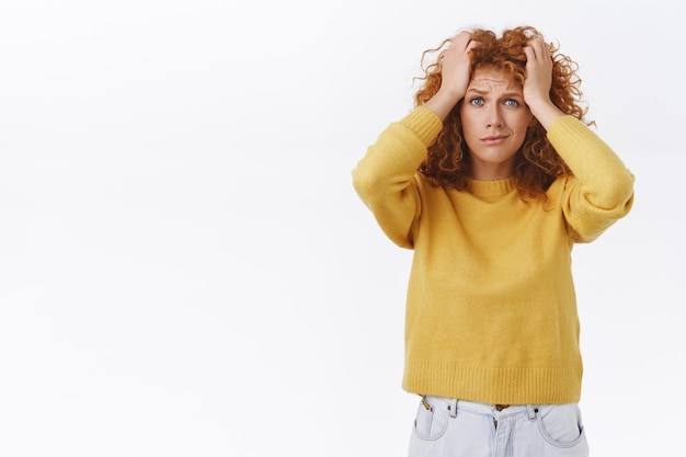 troubled and distressed worried redhead girl with curly hair frowning smirking nervously on white