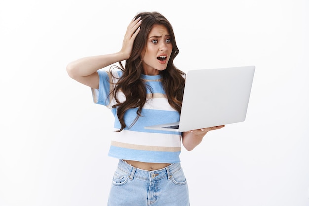 Free photo troubled panicking glamour woman cannot understand what happened to computer, anxiously stare laptop screen