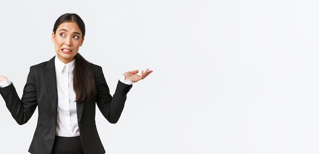 Troubled young female office assistant saleswoman in black suit shrugging and looking away worried d