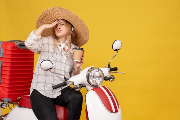 모자를 쓰고 두통이 오토바이에 앉아 티켓을 보여주는 고생 한 젊은 여성