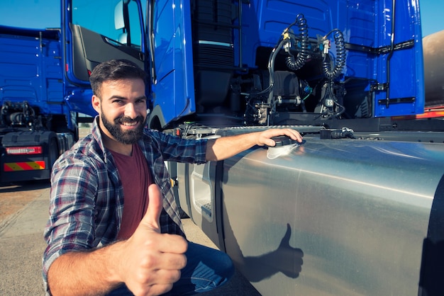トラックの運転手が貯水タンクを開いてトラックに燃料を補給し、親指を立てる