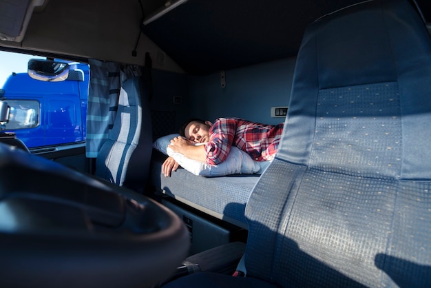 Водитель грузовика спит на кровати внутри салона кабины грузовика