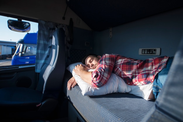 Truck driver sleeping in his cabin after working long routes overtime