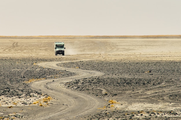 Truck riding through a curvy rocky road making dust