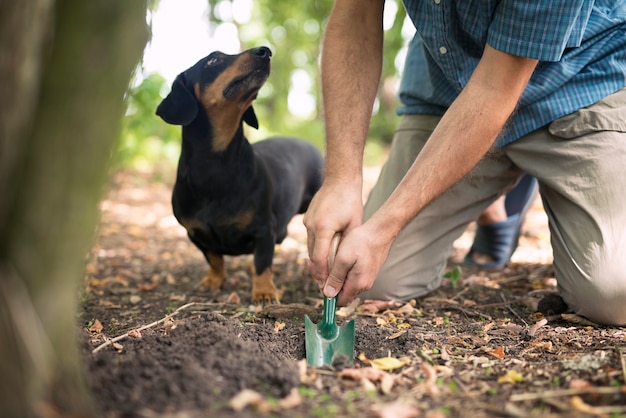森の中でトリュフのキノコを探しているトリュフハンターと彼の訓練された犬