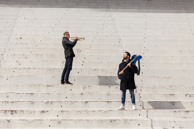 Trumpet player and guitarist on concrete stairs