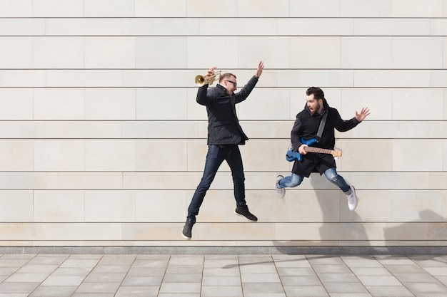 Trumpet player and guitarist jumping in urban environment