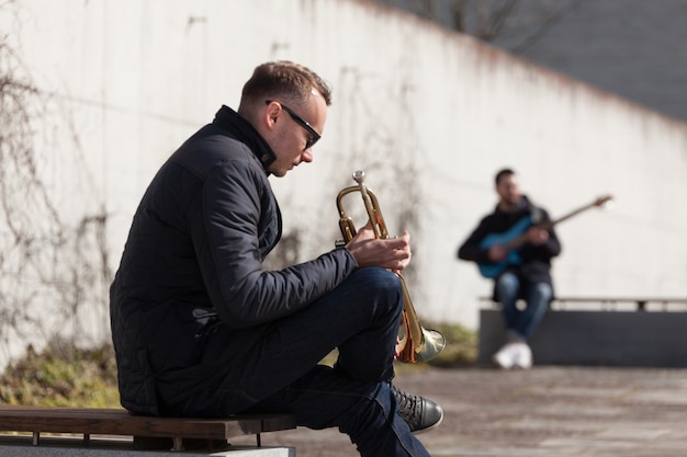 Trumpet player and guitarist sitting in urban environment