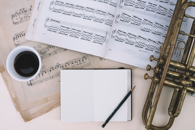 Trumpet and sheet music near drink and notepad