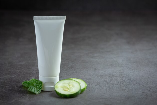 Tube cream  with cucumber slices on dark background