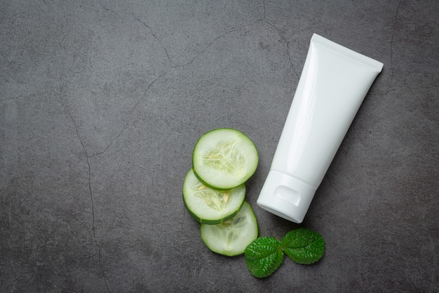 Tube cream  with cucumber slices on dark background