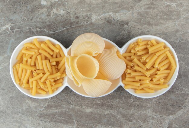 Tube and seashell pasta in white bowls