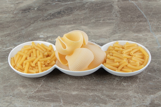 Tube and seashell pasta in white bowls