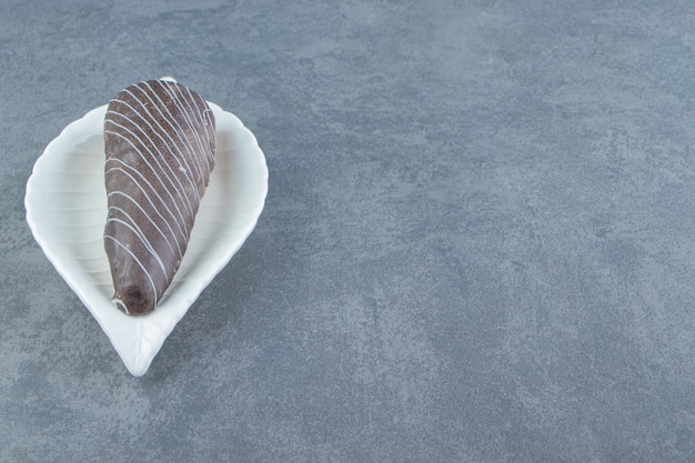 Tube-shaped pastries glazed with chocolate on white plate. 