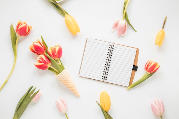 Tulip flowers in waffle cone with blank notebook 