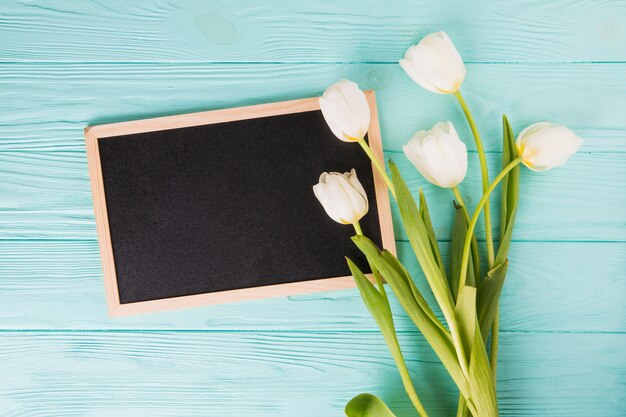 Tulip flowers with blank chalkboard on wooden table
