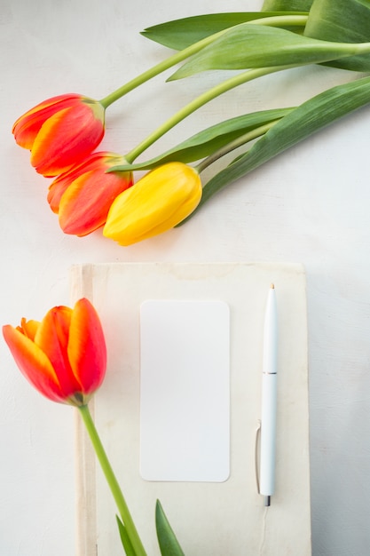 Free photo tulips and envelope with pen placed on desk