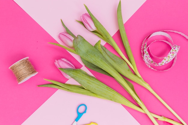 Free photo tulips and ribbon on pink table