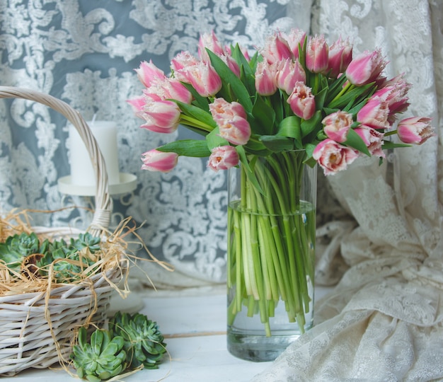 Tulips in a vase and tulle curtain on the font