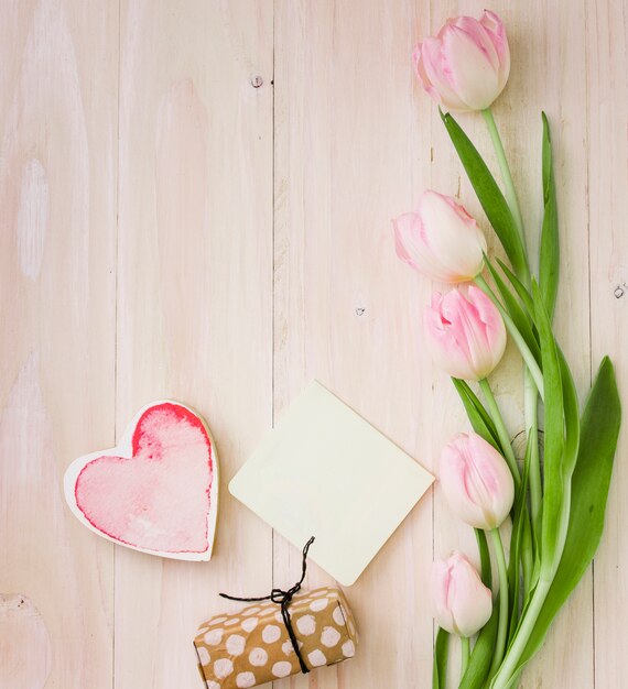 Tulips with gift box and paper on table