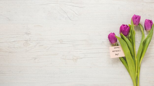 Tulips with Happy Mothers Day inscription on table
