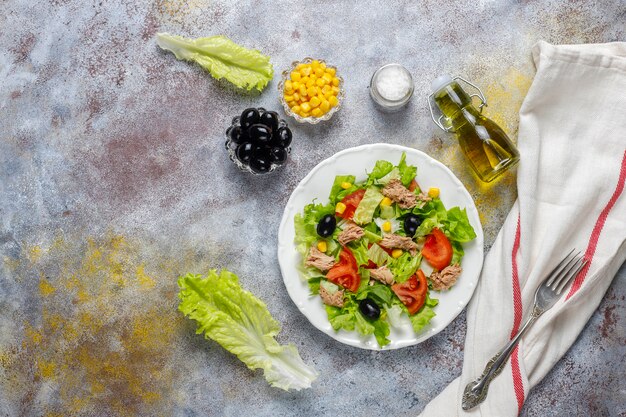 Салат из тунца с листьями салата, маслинами, кукурузой, помидорами, вид сверху