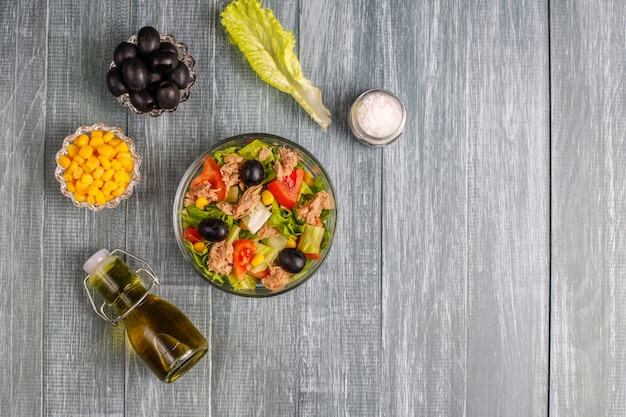 Tuna salad with lettuce, olives, corn, tomatoes, top view