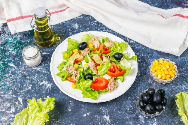 Салат из тунца с листьями салата, маслинами, кукурузой, помидорами