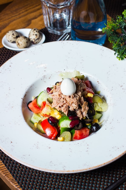 Foto gratuita insalata di tonno con pomodori, cetrioli, mais e uova in cima