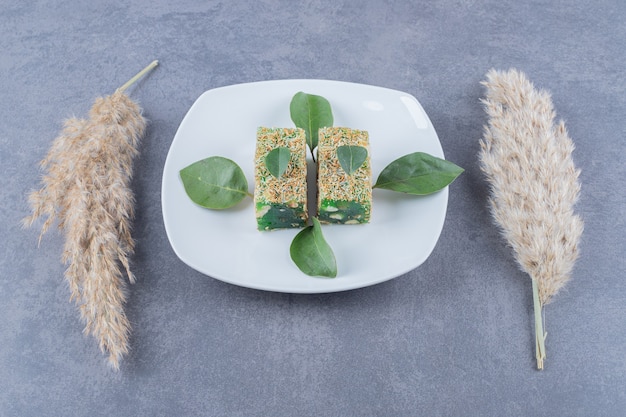 Free photo turkish delight. lokum with hazelnuts on white plate over grey background.