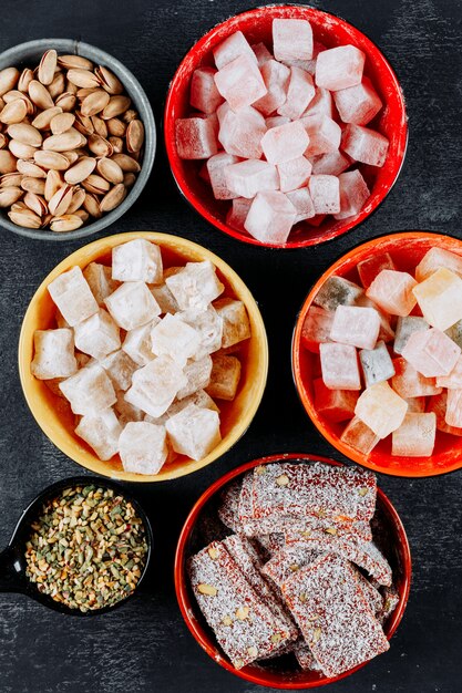 Turkish delight lokums in a bowls with pistachio side view on a black textured background