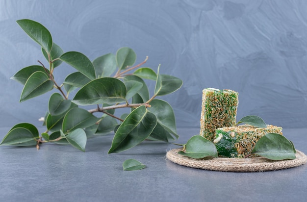 Turkish delight rahat lokum with hazelnutsa and decorative leaves on grey background.