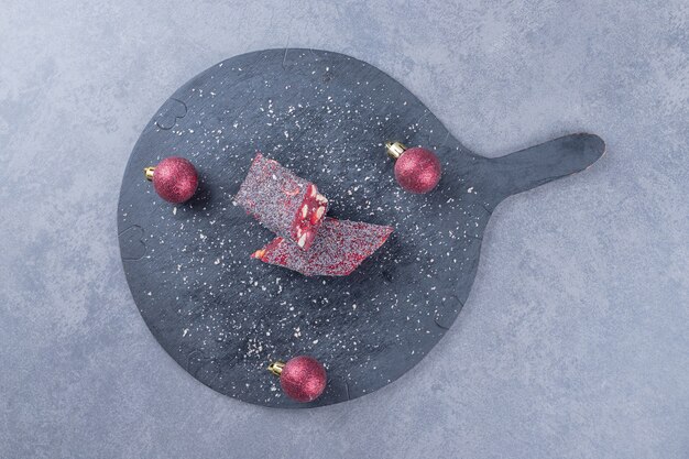 Turkish delight rahat lokum with pistachios on black cutting board.