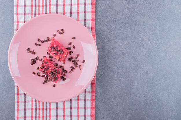 Turkish delight rahat lokum with pistachios and dry raisins on pink plate