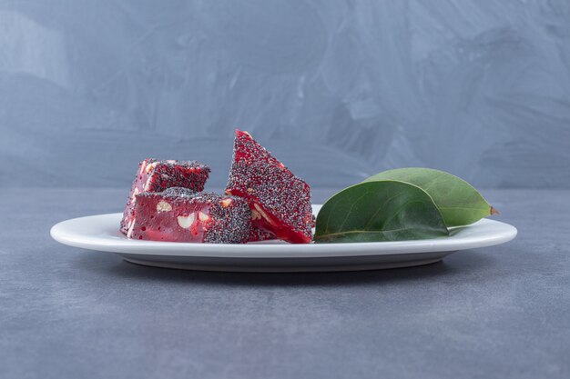 Free photo turkish delight rahat lokum with pistachios on white plate over grey background.