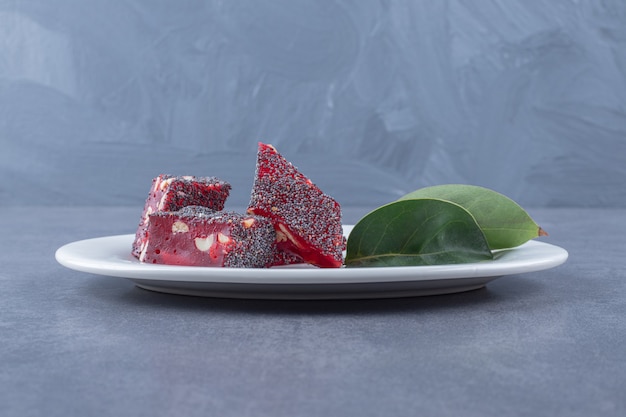 Turkish delight rahat lokum with pistachios on white plate over grey background.