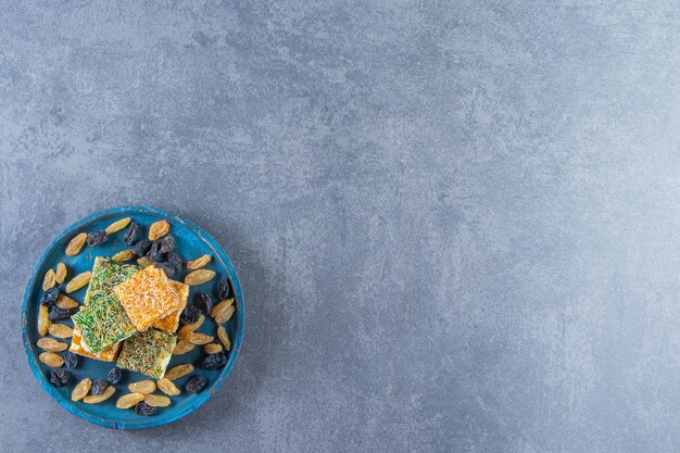 Free photo turkish delights and raisins on a wooden plate, on the marble background.