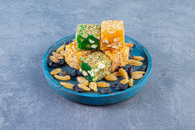 Turkish delights and raisins on a wooden plate, on the marble surface