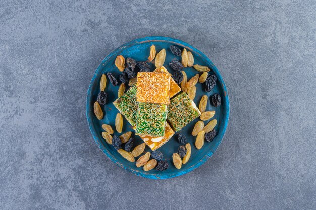 Turkish delights and raisins on a wooden plate, on the marble surface