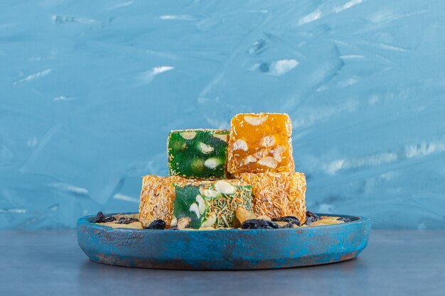 Turkish delights and raisins on a wooden plate, on the marble surface