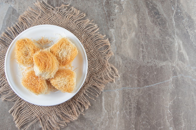 Turkish dessert kadayif on a plate on towel on marble.