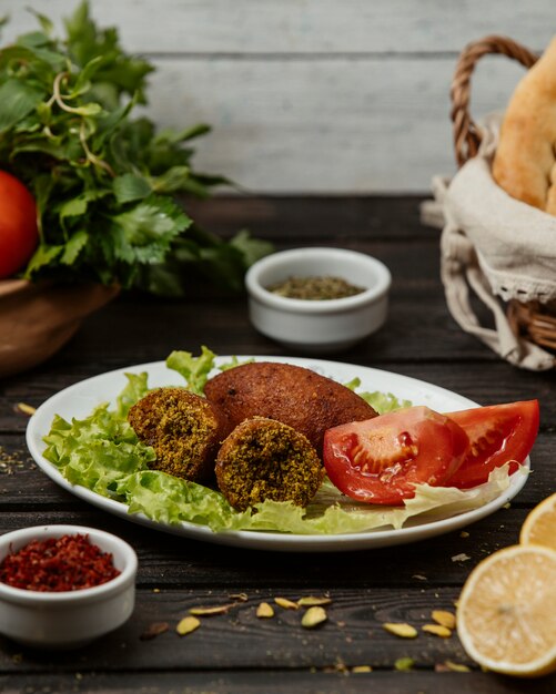 turkish kibbeh stuffed meat balls served with tomato, and lettuce