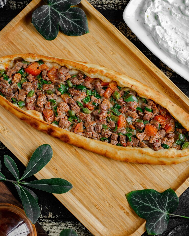 Free Photo turkish pide pizza with meat and vegetable stuffing inside wooden tray.