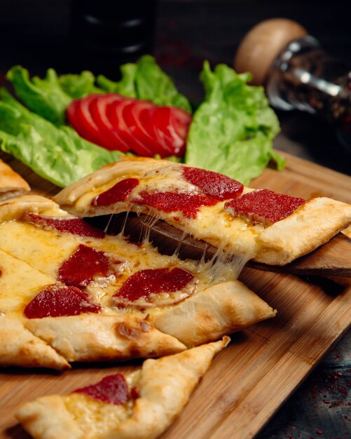 Turkish pide pizza with pepperoni and melted cheese.