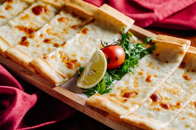 Turkish pide with melted cheese, tomato, lemon and chopped parsley.
