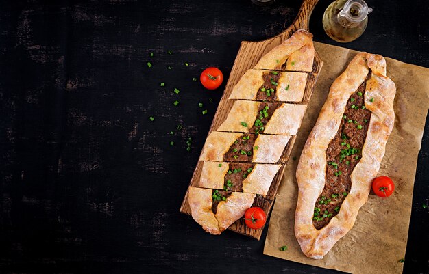 Turkish pide with minced meat, Kiymali Pide. Traditional Turkish cuisine. Turkish pizza Pita with meat. Top view, overhead