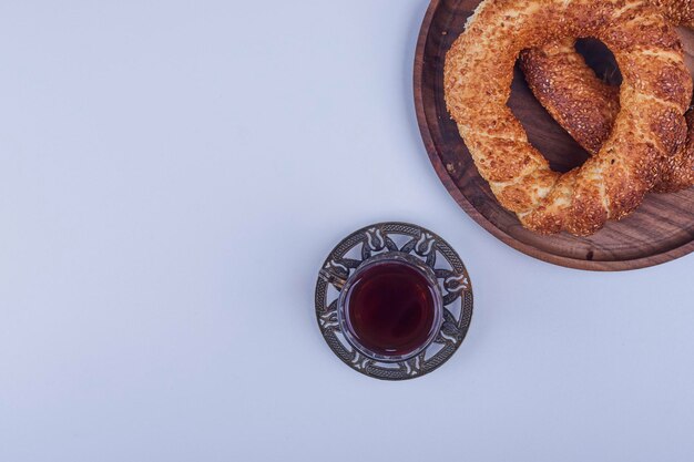 Турецкий симит на деревянной тарелке с бокалом чая, вид сверху. Фото высокого качества