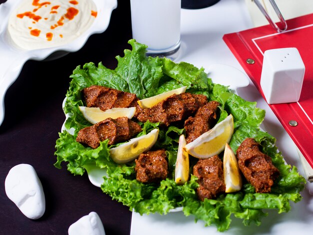 Turkish spicy raw meatballs cig kofte served with lemon and lettuce