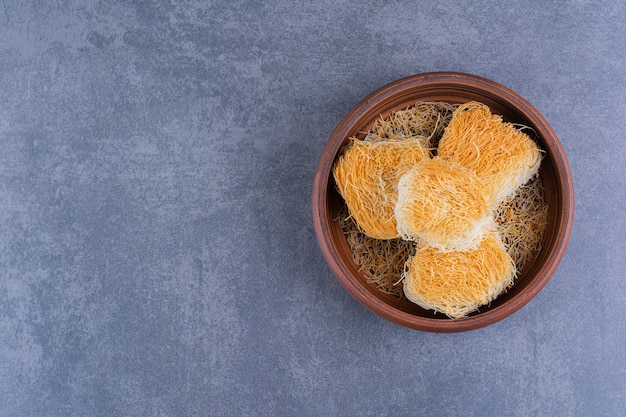 Turkish sweet desserts in a clay plate on a stone .