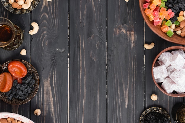 Turkish tea; dried fruits; raisins; nuts and lukum on black textured wooden desk